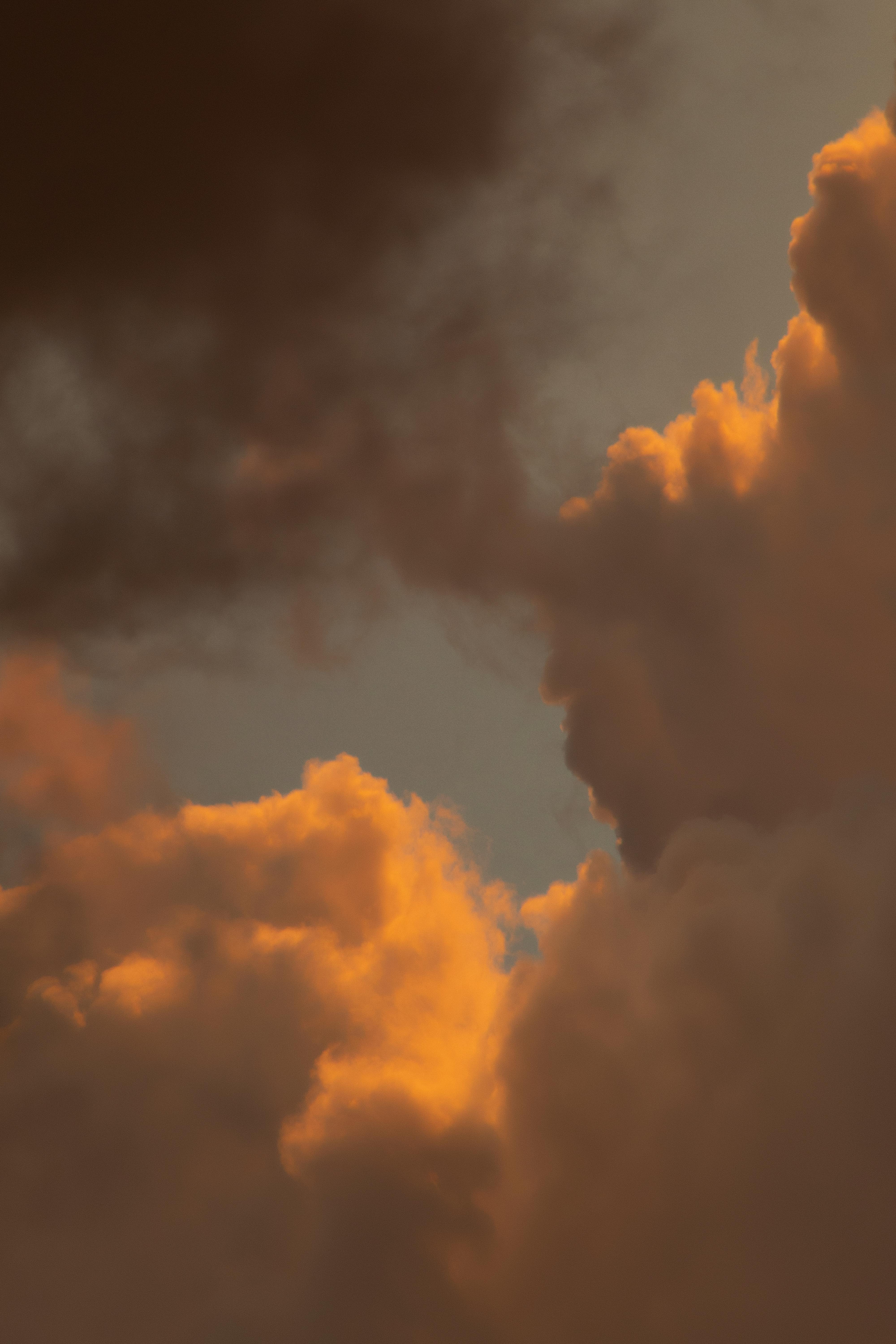 White fluffy cumulus clouds floating on blue sky with dark haze in daylight in nature with smoke in foreground outside