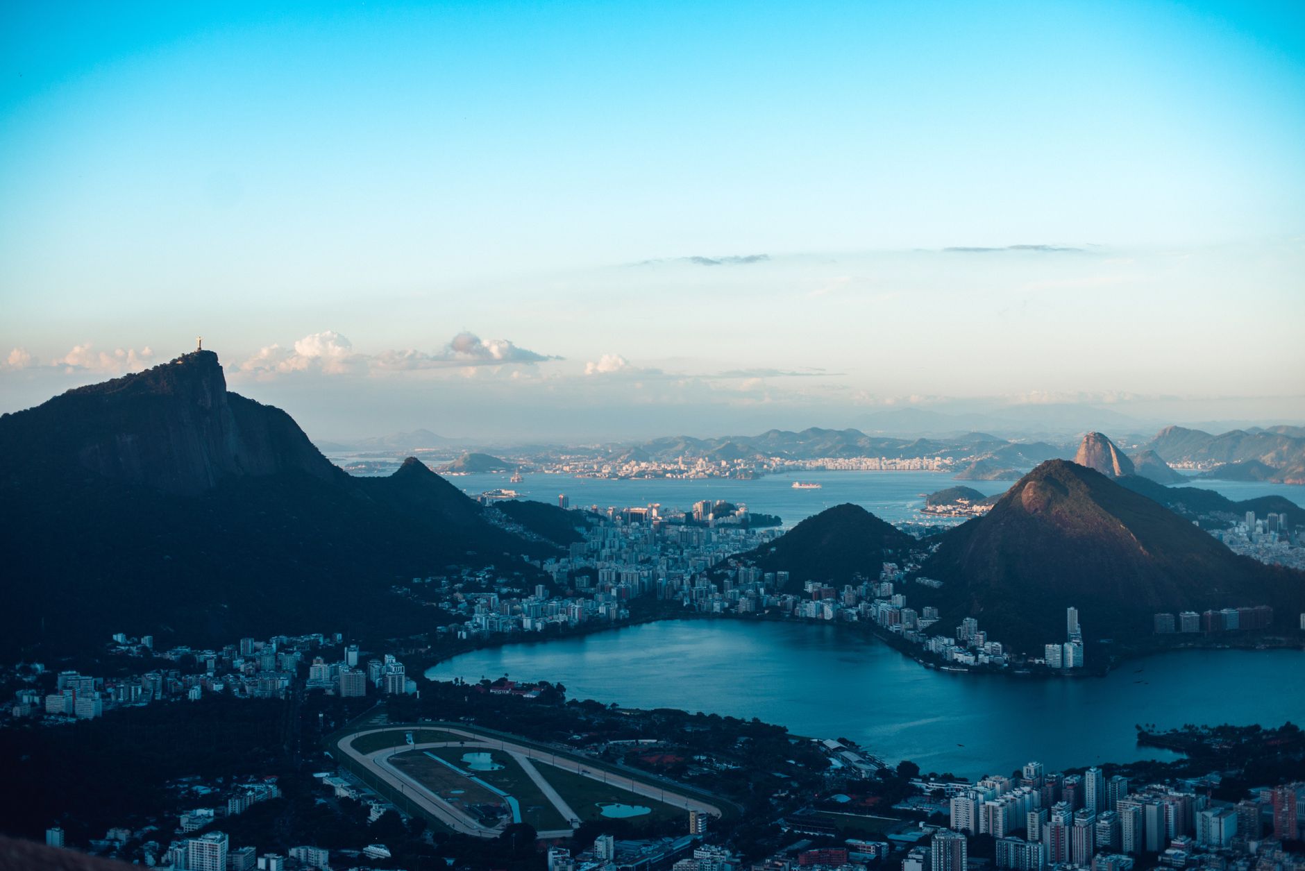 Aerial view of picturesque scenery of sea surrounded by mountains with buildings located on coastline against cloudy sky in summer evening