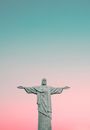 Low angle of sculpture of Christ redeemer with open arms placed against pink sky in famous Brazil at sunset time