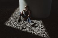 Woman in Blue Tank Top and Blue Denim Jeans Sitting on Gray Concrete Floor