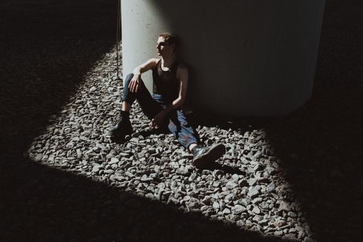 Woman in Blue Tank Top and Blue Denim Jeans Sitting on Gray Concrete Floor
