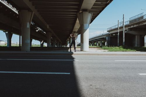 Free Dancer striking a pose beneath an urban highway bridge, showcasing street style. Stock Photo