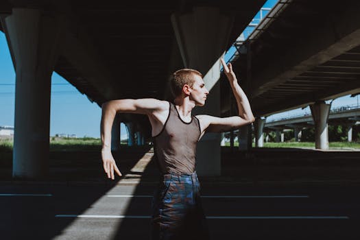 A male dancer poses under a bridge, showcasing street dance form and expression in urban setting.