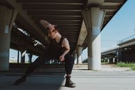 一名男舞者在城市桥下，于阳光明媚的日子里摆出街舞风格的姿势