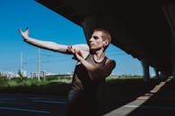 Man in Black Tank Top and Blue Denim Jeans Standing on Gray Concrete Pavement