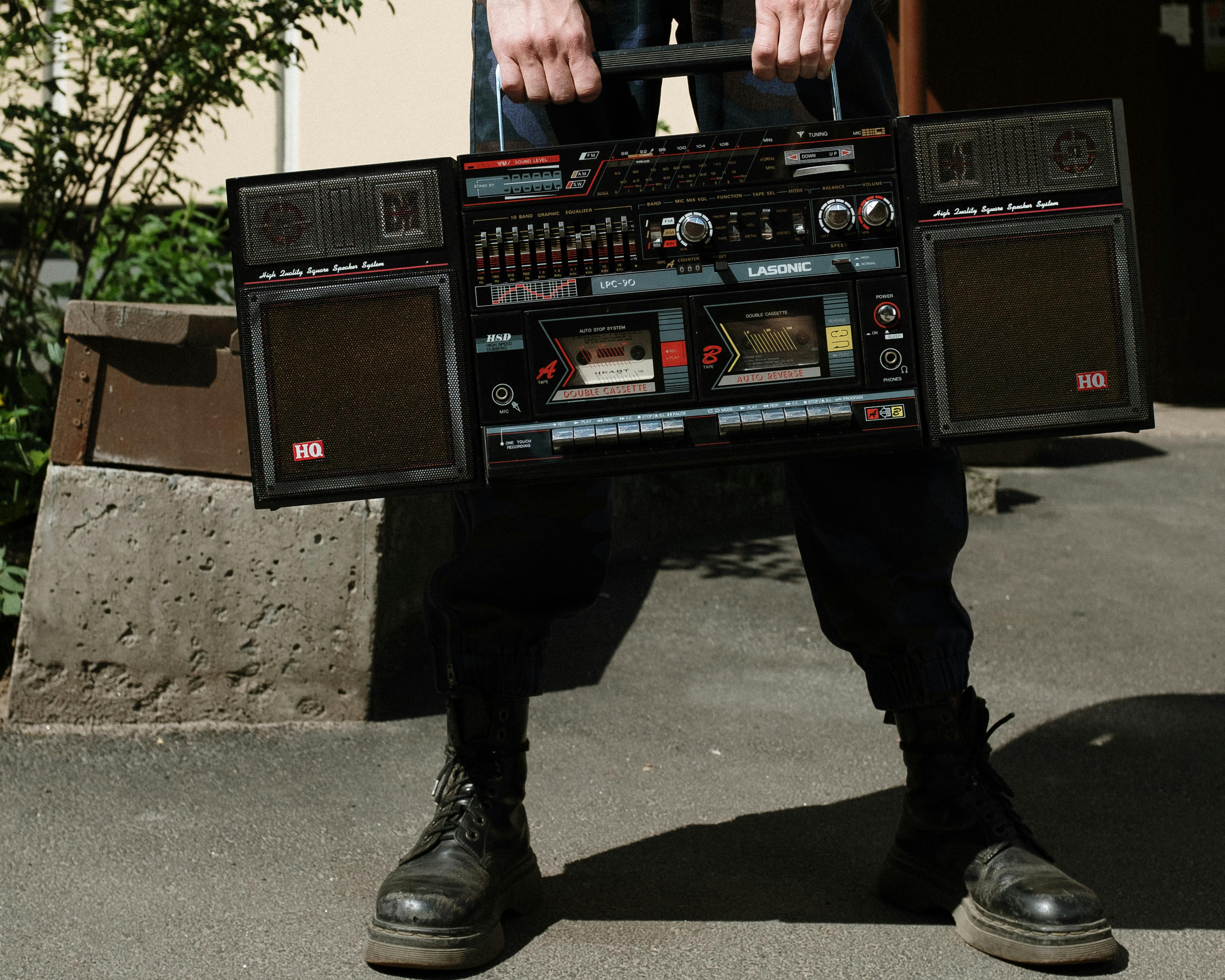 man in black leather boots holding black and red radio