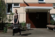 一个年轻人拿着一台老式音箱站在建筑立面