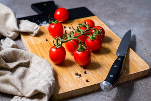 Free Red Tomatoes and Knife on Brown Wooden Chopping Board Stock Photo