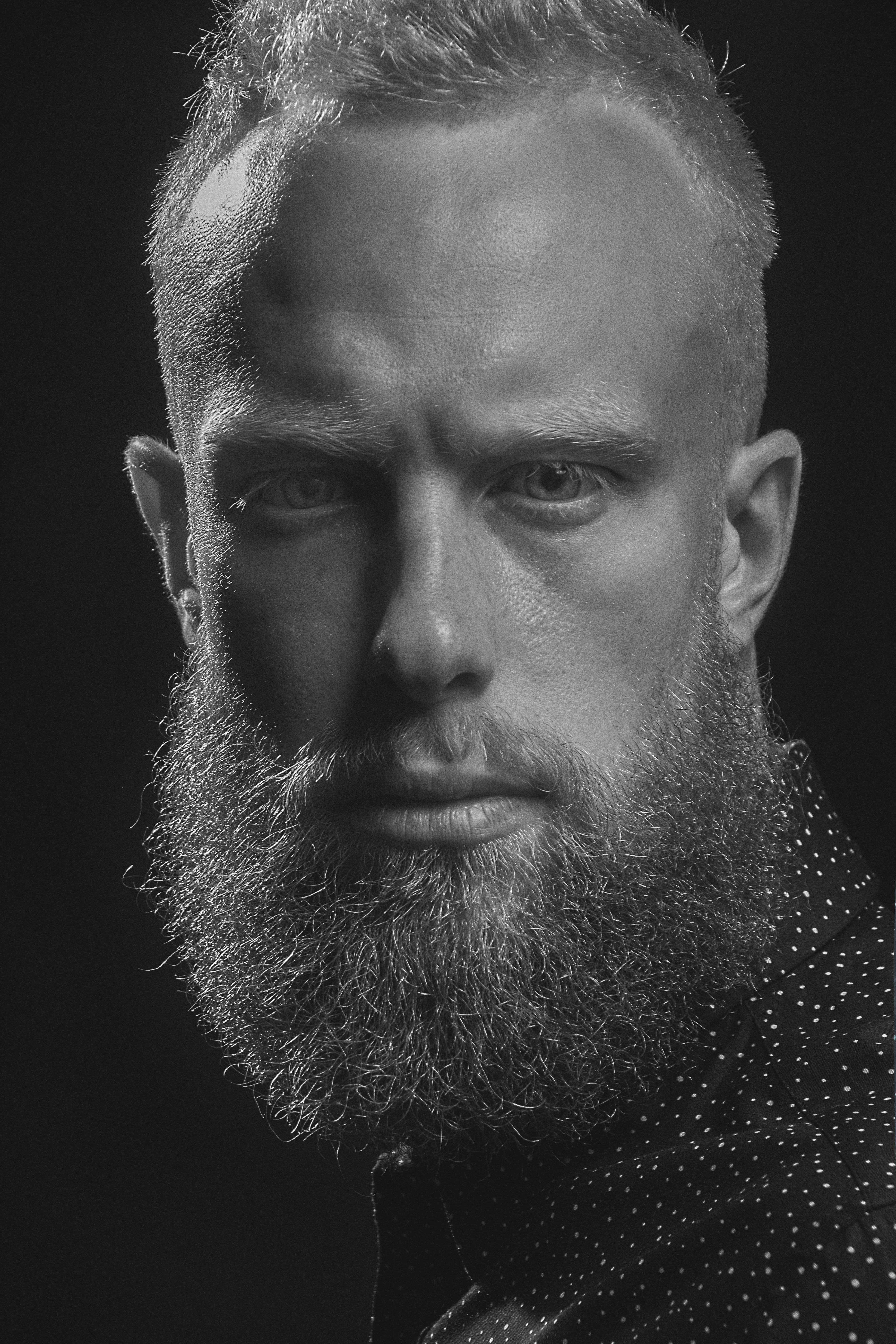 Grayscale portrait of a bearded caucasian man with intense expression.