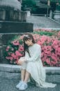 Woman Sitting next to Flowers