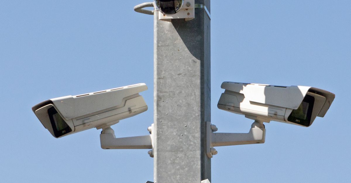 An outdoor security camera mounted on a house wall capturing the front yard area.