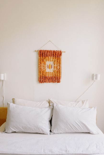 Contemporary bedroom with pillows on bed near white wall with colorful decor in house
