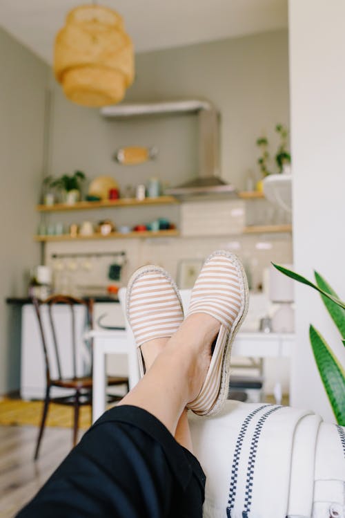 Crop woman resting on sofa near modern kitchen in house