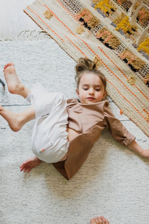 Barefoot girl having fun on soft carpet at home