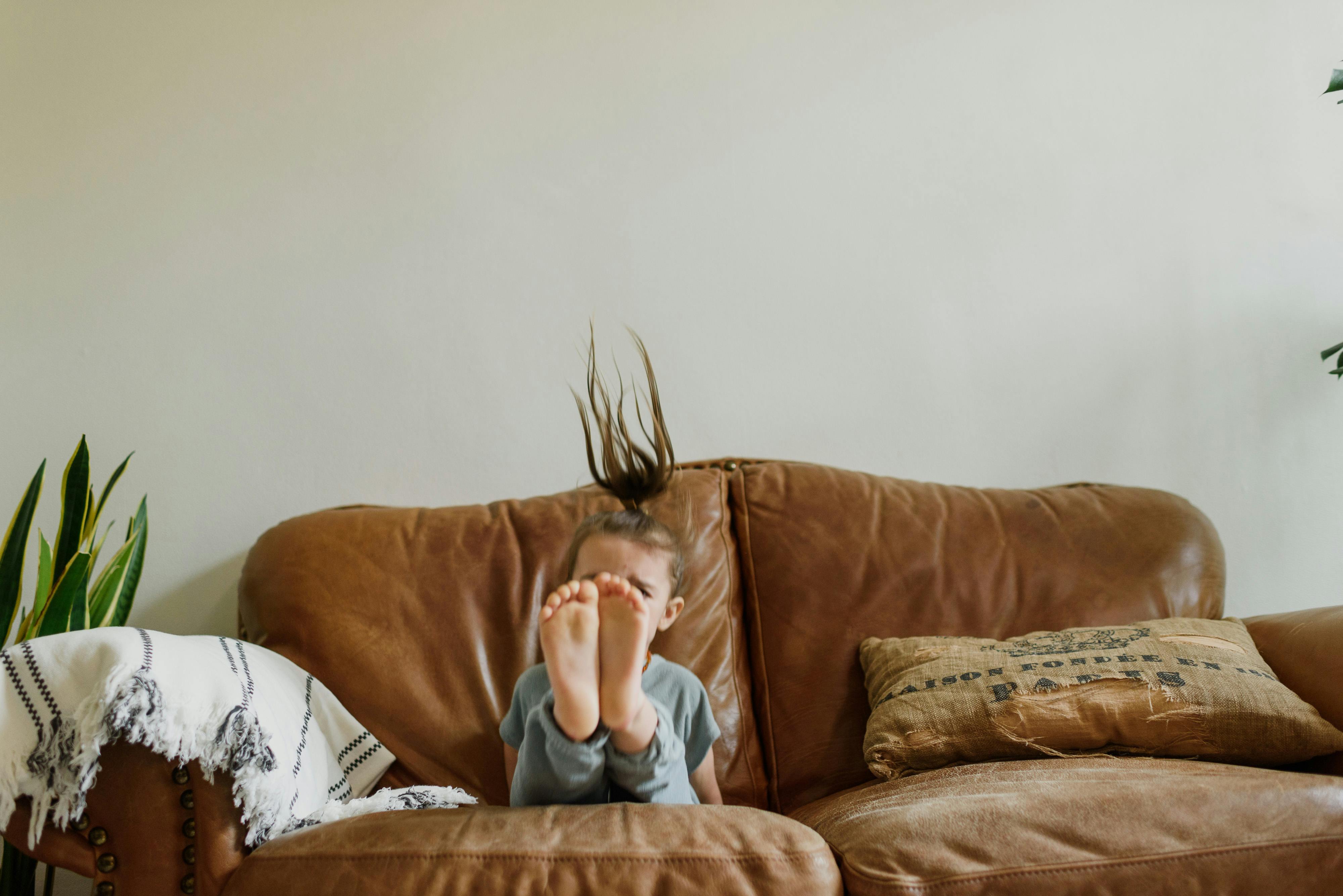 Unrecognizable girl jumping on cozy sofa at home · Free Stock Photo