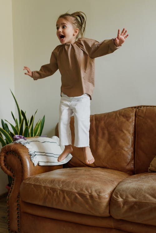 Excited girl jumping on couch in living room