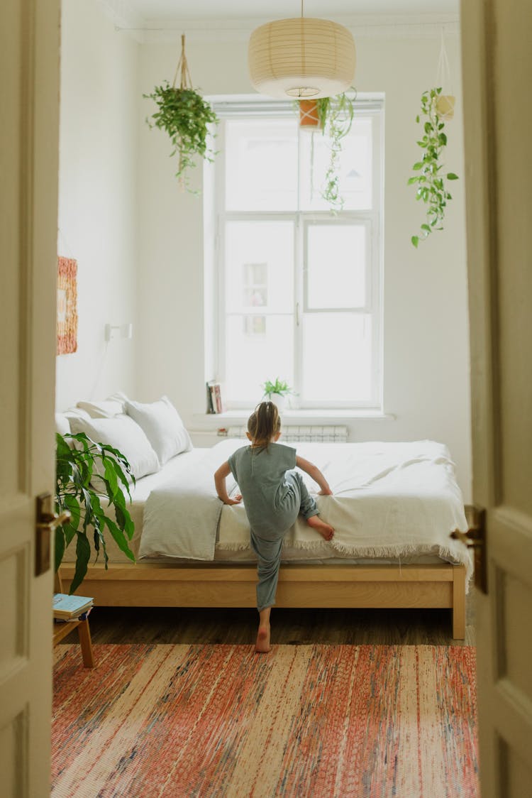 Faceless Girl Climbing Onto Bed In Modern Bedroom