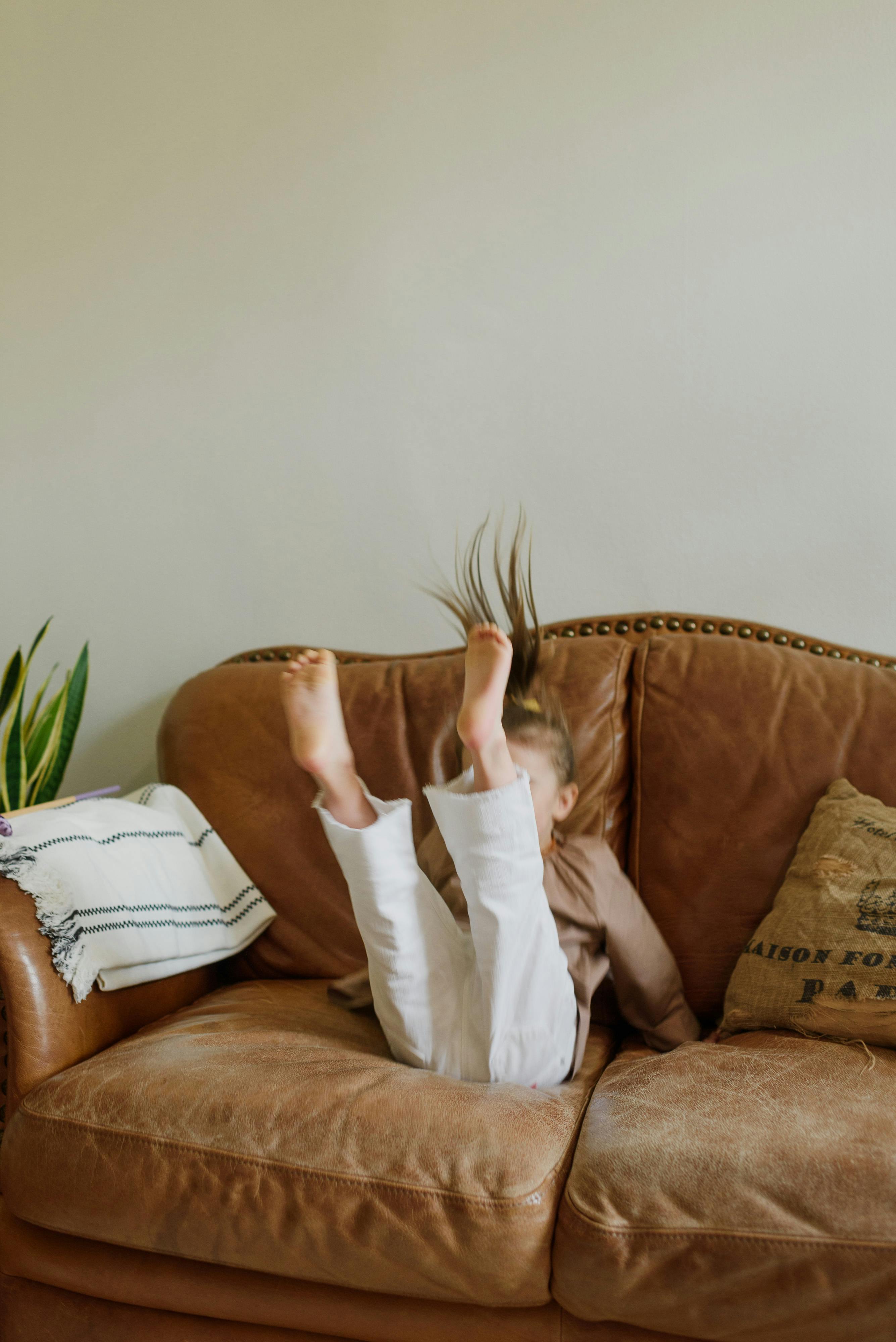 anonymous child having fun on sofa in living room