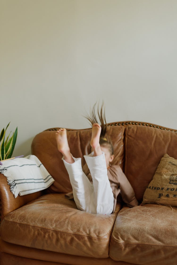 Anonymous Child Having Fun On Sofa In Living Room