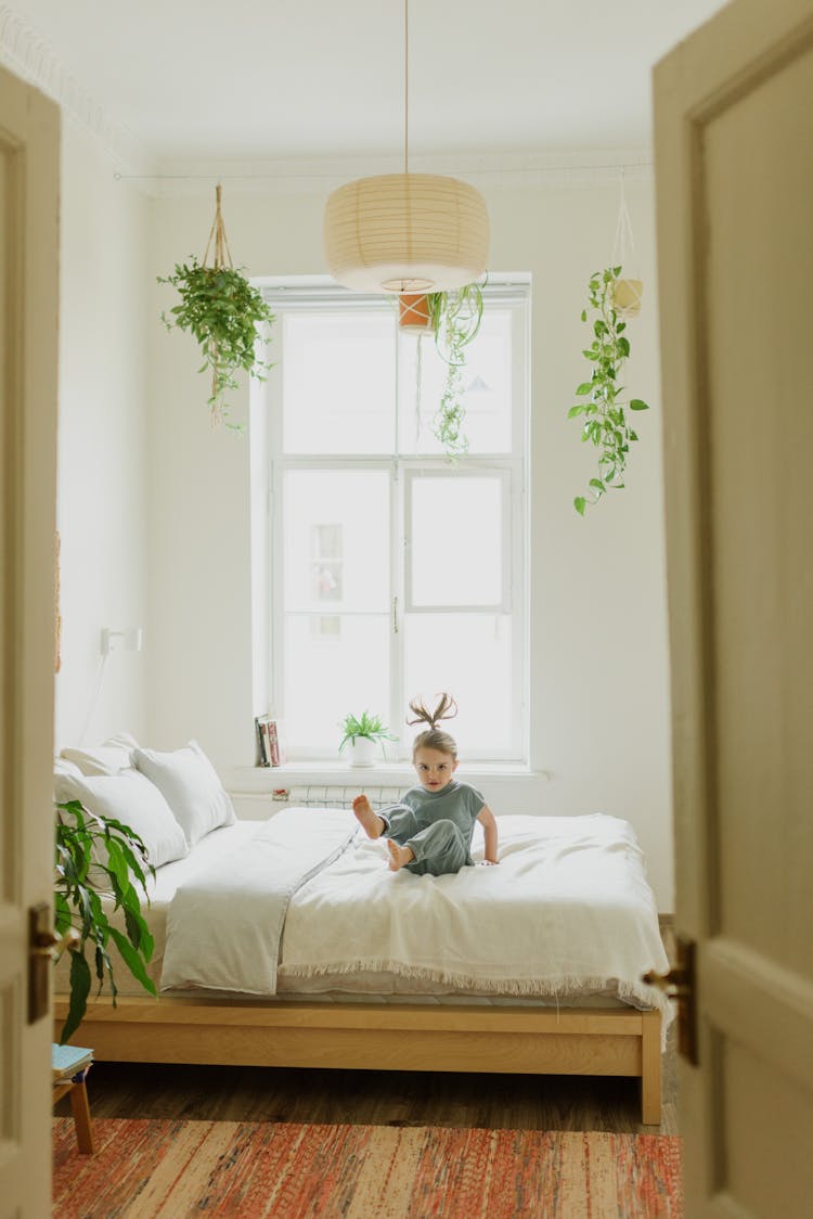 Carefree Girl Jumping On Bed At Home