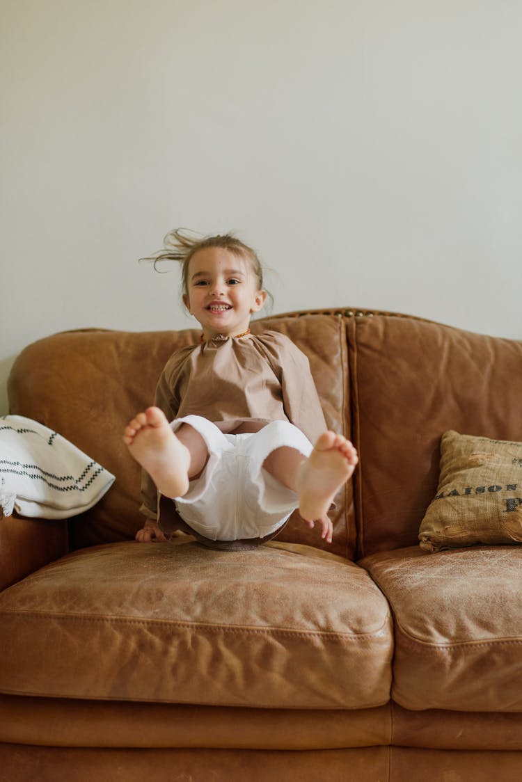 Cheerful Girl Jumping On Sofa At Home