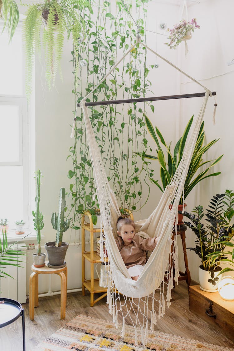 Cute Girl Resting In Hammock In Room With Plants