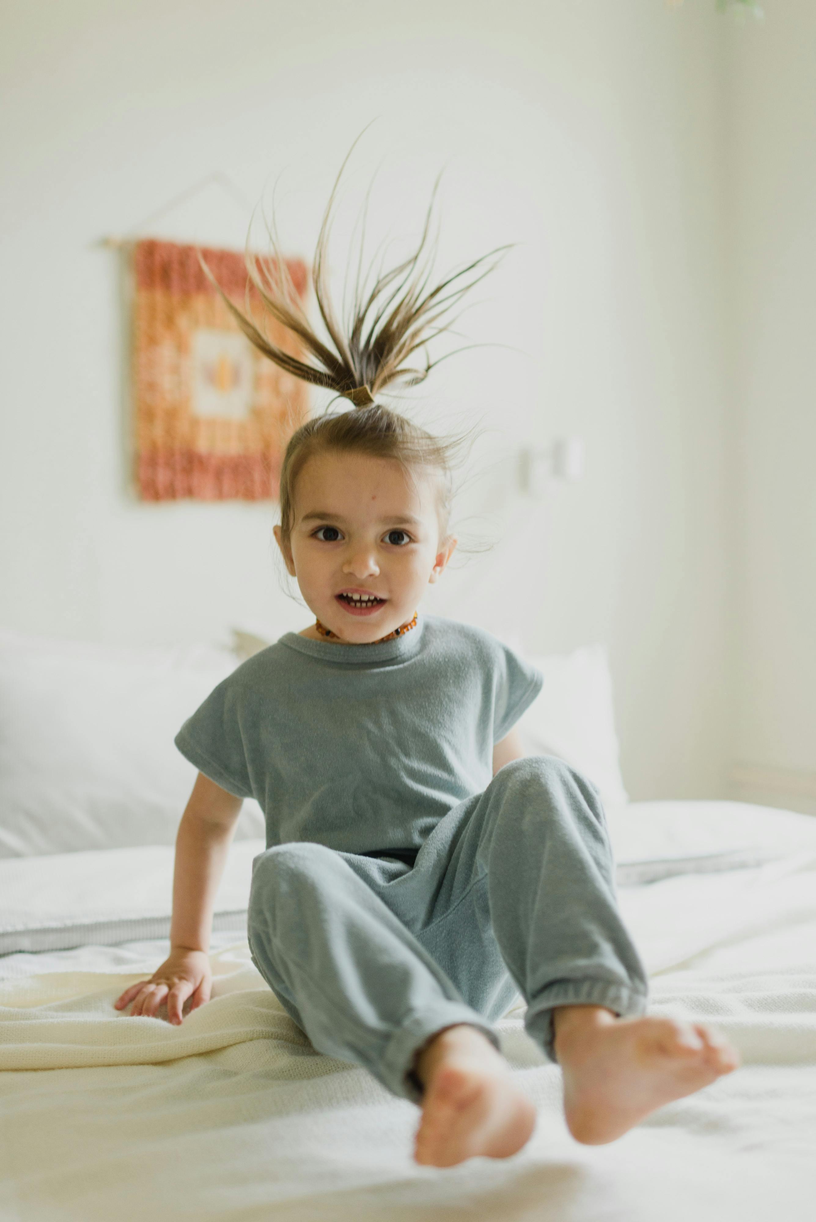 carefree girl with flying hair jumping on bed