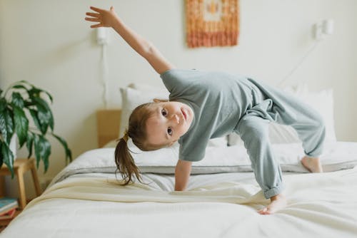 Free Adorable little girl having fun on bed at home Stock Photo