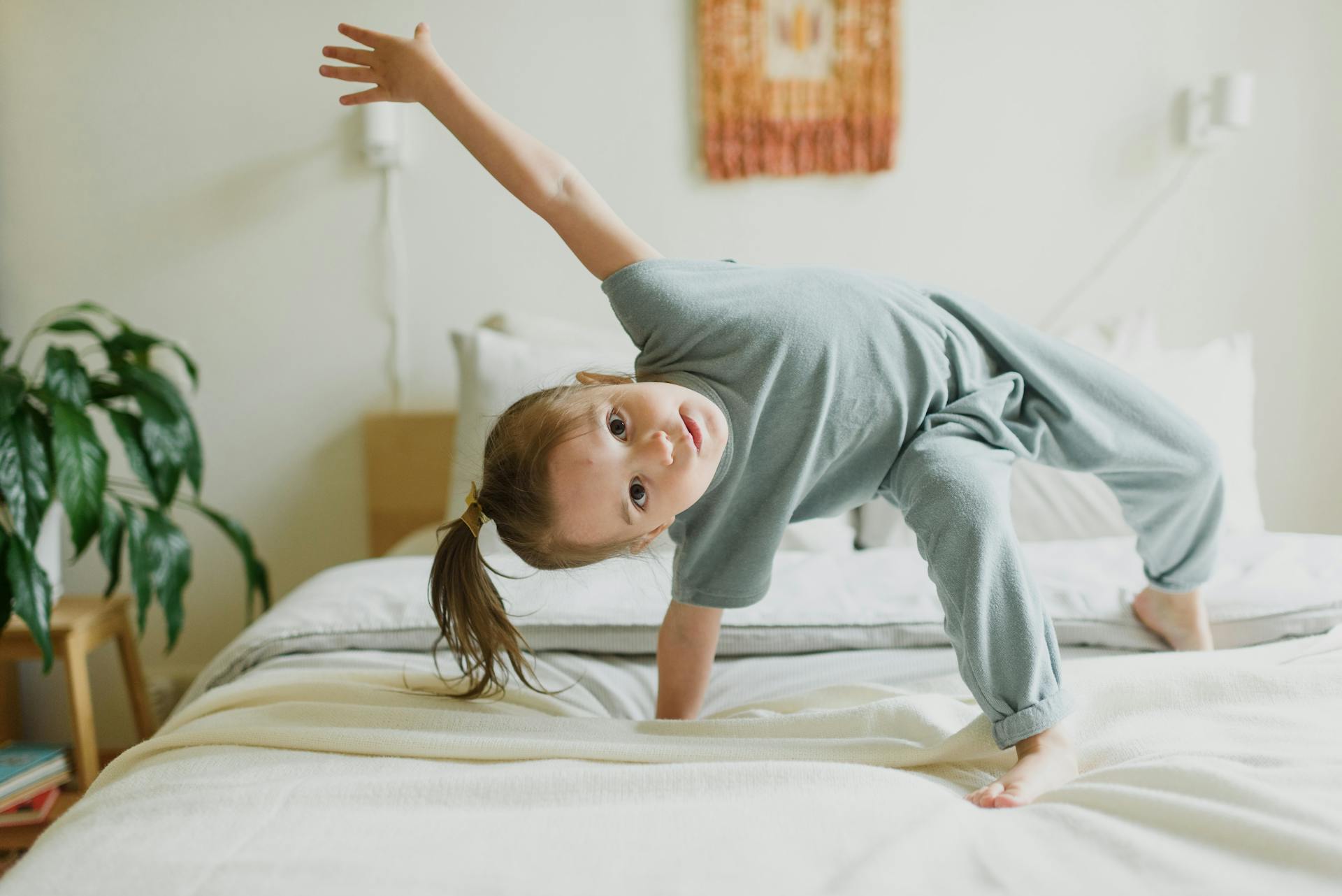 Adorable little girl having fun on bed at home