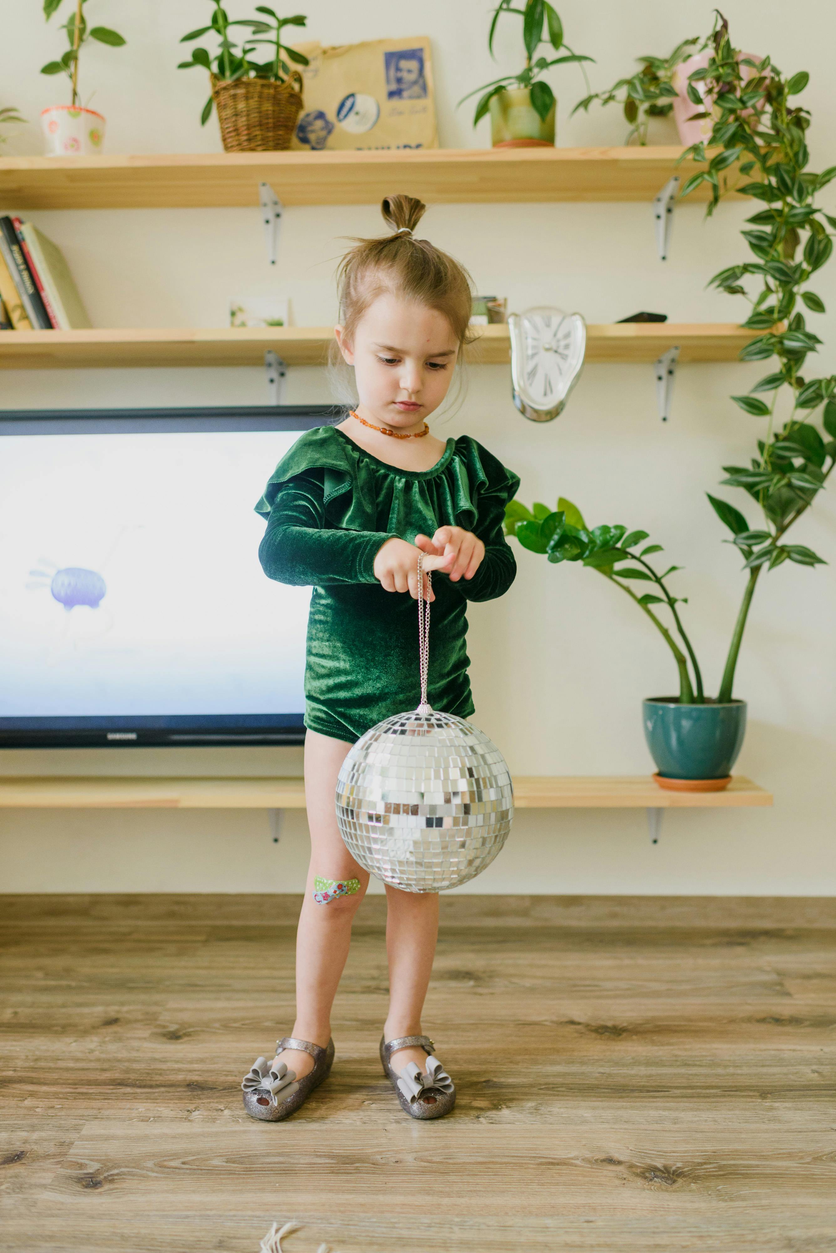 adorable little child playing with mirrored ball at home