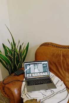 A cozy home office setting featuring a leather chair, laptop, and snake plant for a modern workspace vibe.
