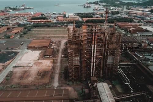 Aerial view of factory with shabby buildings and rusty industrial constructions located in harbor of city