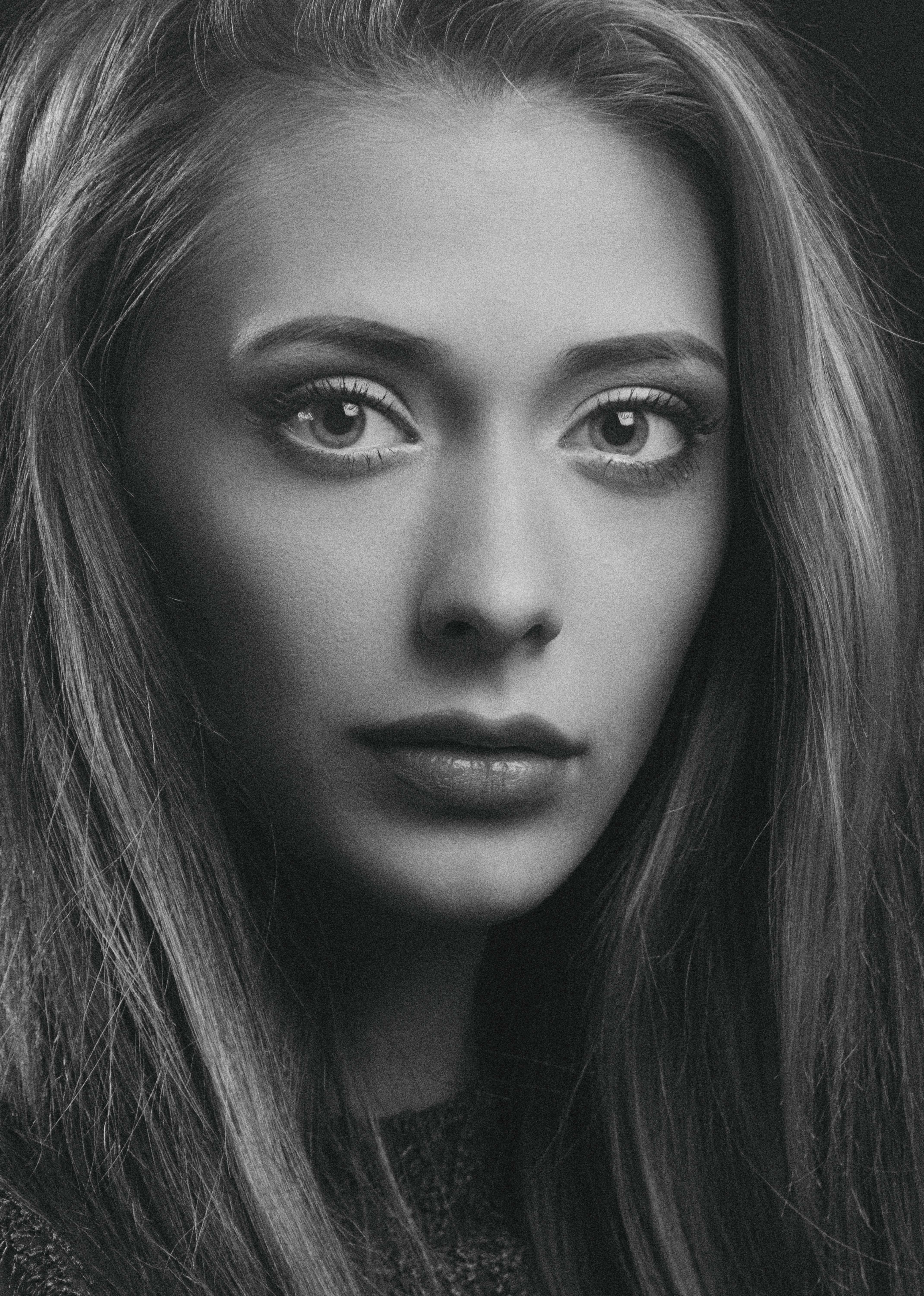 Stunning close-up portrait of a young woman in black and white, showcasing deep emotions.