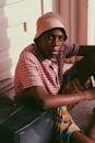 Black man in bucket hat sitting on floor