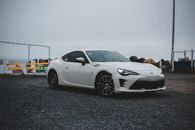 Comfortable contemporary automobile with white bodywork and black wheels on empty parking place