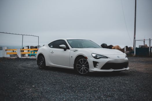 Comfortable contemporary automobile with white bodywork and black wheels on empty parking place