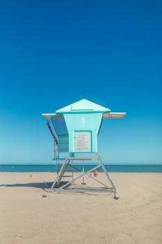 A serene lifeguard station stands on the sandy shores of Santa Barbara under a clear blue sky.