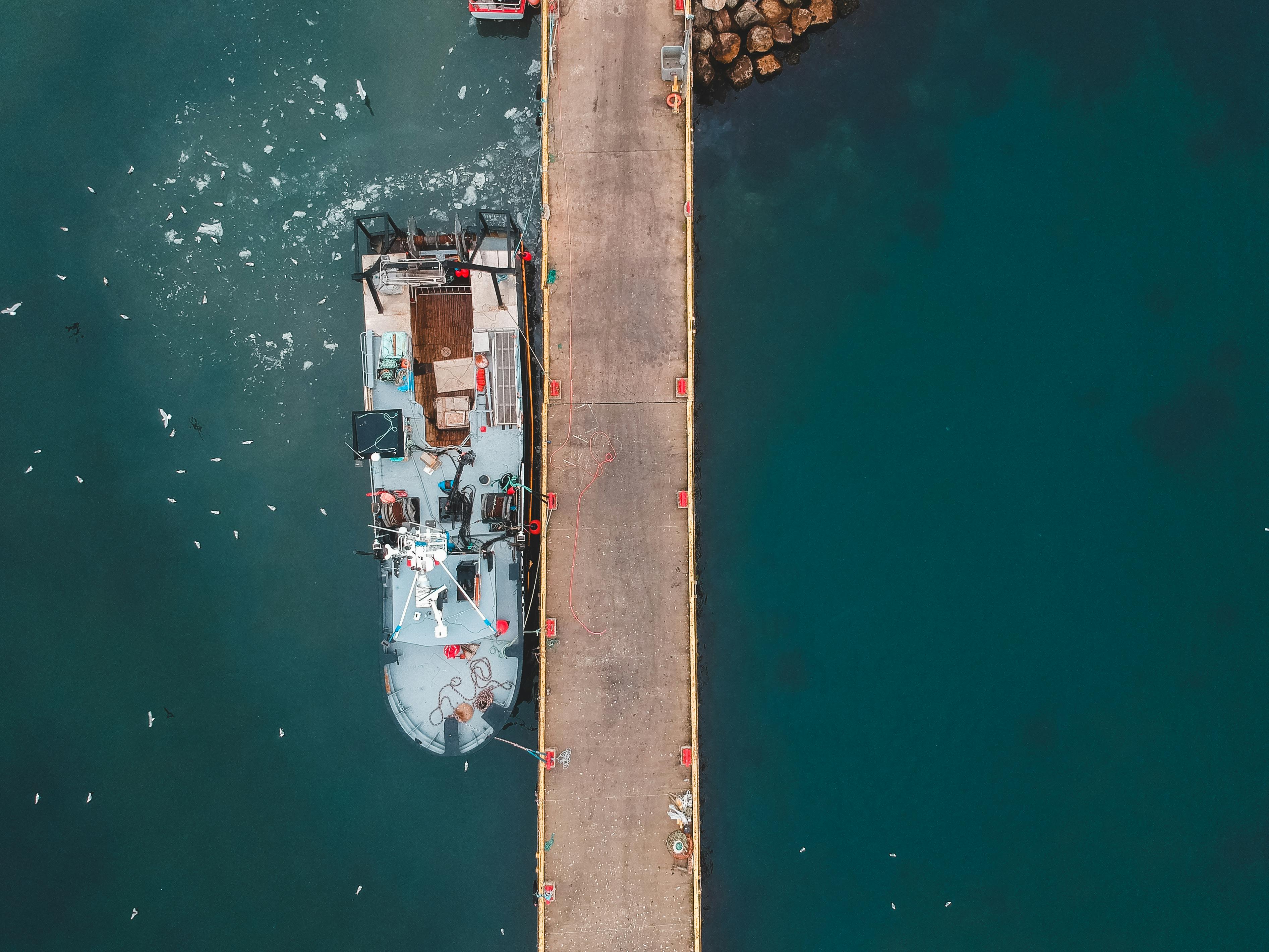 aged motor boat moored on sea near dock