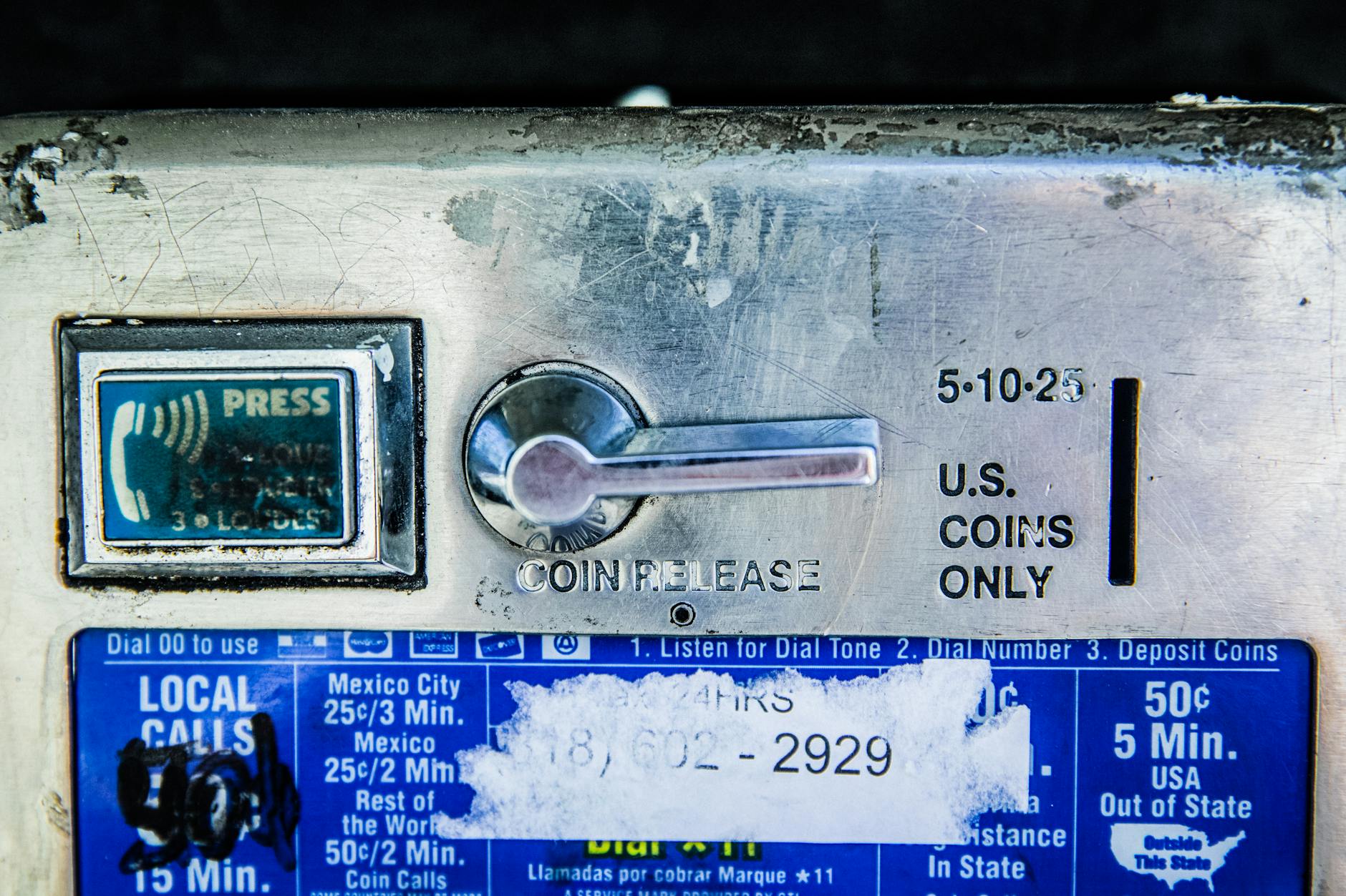 Detailed view of a vintage payphone coin slot, showing coin release and payment instructions.