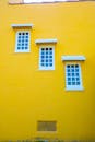 这座充满活力的黄色建筑立面，其特色是三个以交错图案排列的小白框窗户