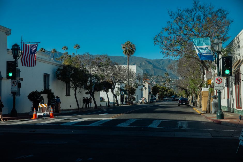 A scenic street view in Santa Barbara on a sunny day with flags and mountains in the background.