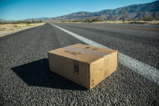 空旷的沙漠道路上，一只孤独的纸板箱捕捉了孤独的本质