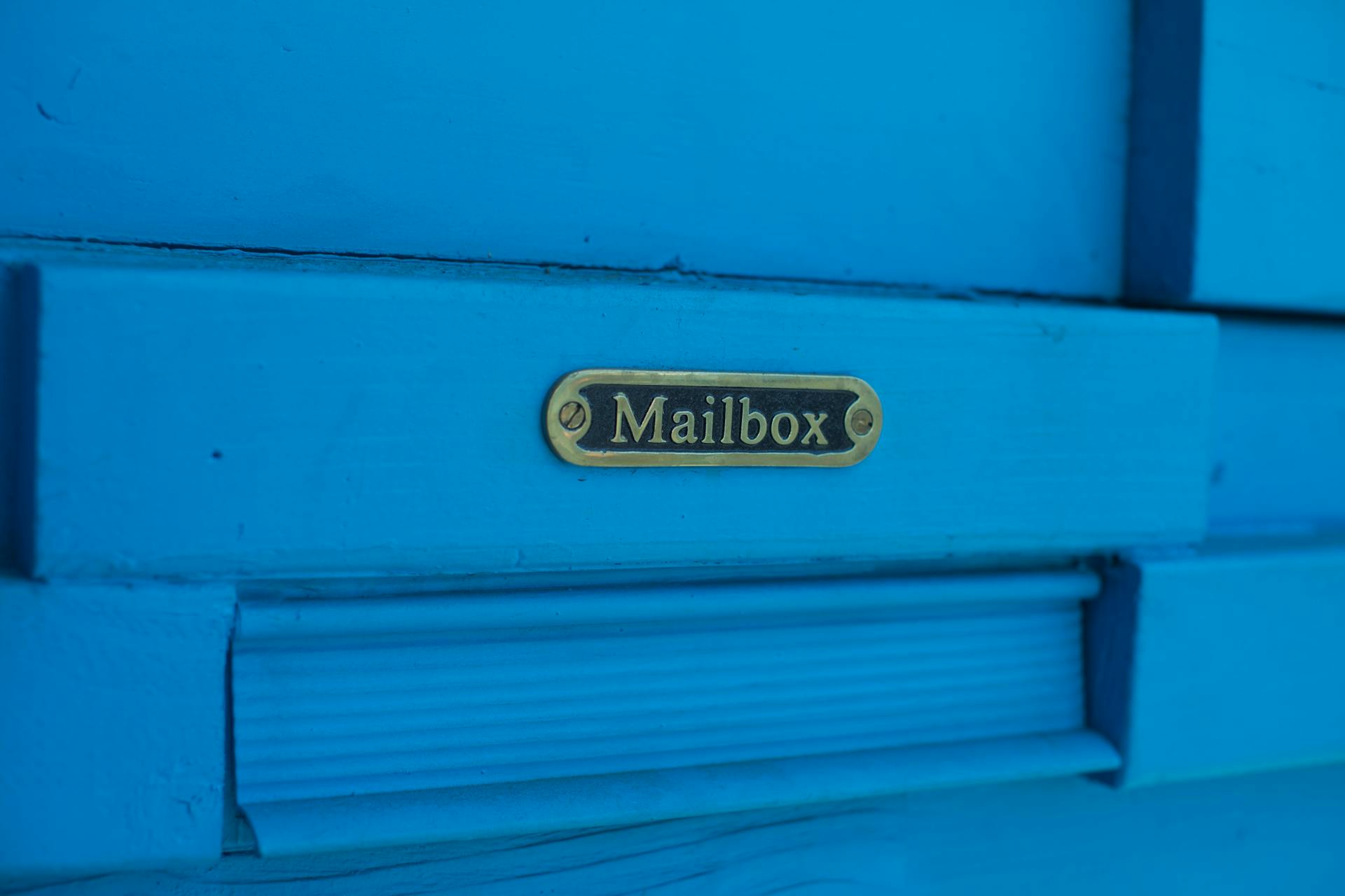 Close-Up Photo of Mailbox Metal Sign on Blue Painted Wall