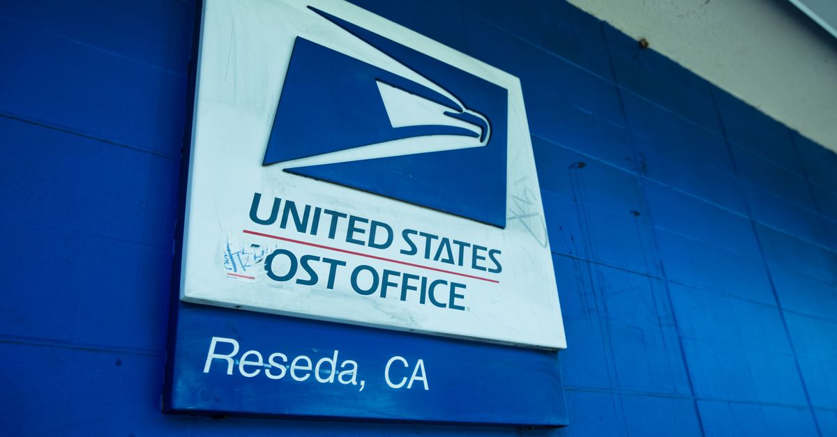 Close-up of the United States Post Office sign against a blue wall in Reseda, CA.