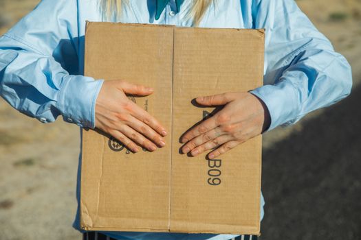 Person in Blue Long Sleeve Shirt Holding Brown Cardboard Box