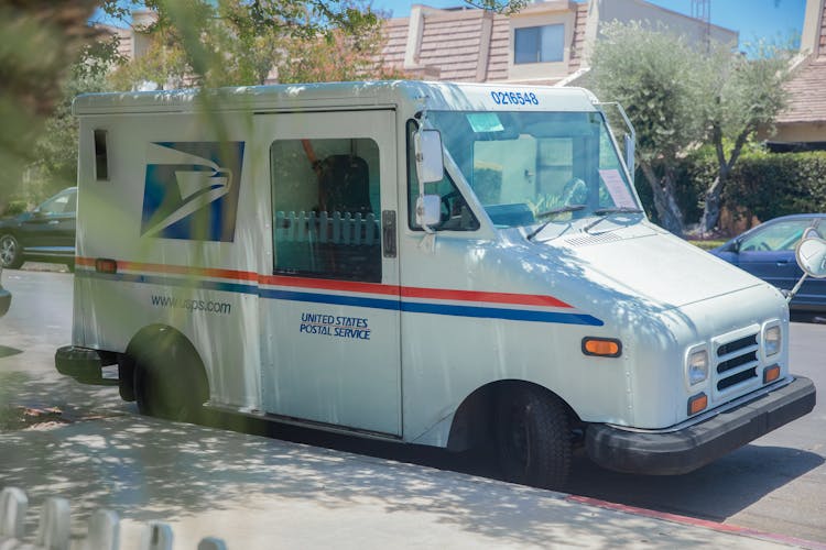 Postal Service Van Parked On A Street Sidewalk