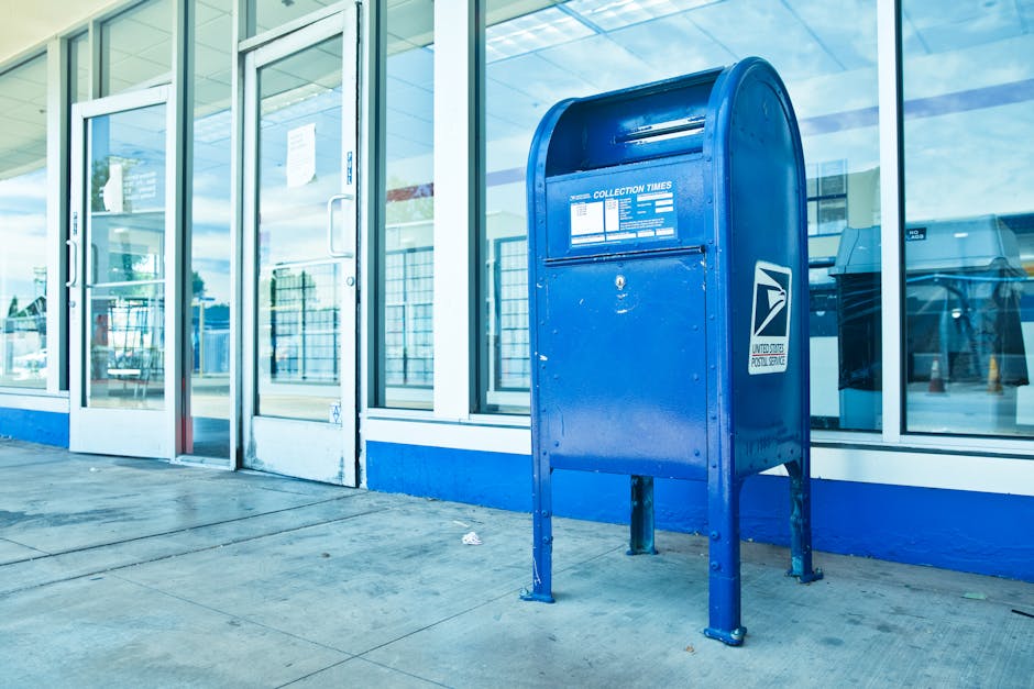 Photo by Ekaterina Belinskaya USPS blue mailbox against a post office facade in Los Angeles, CA.