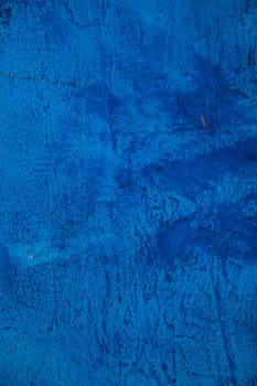 A close-up view of a vivid blue textured concrete wall, ideal for backgrounds or wallpapers.
