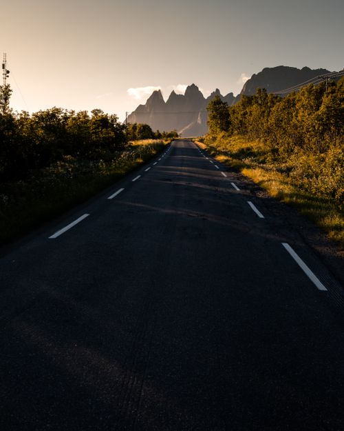 Free Beautiful view of an empty road leading towards mountains in Troms og Finnmark during golden hour. Stock Photo