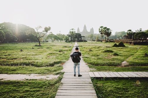 Back View of Person Standing on Pathway Between Green Grass 